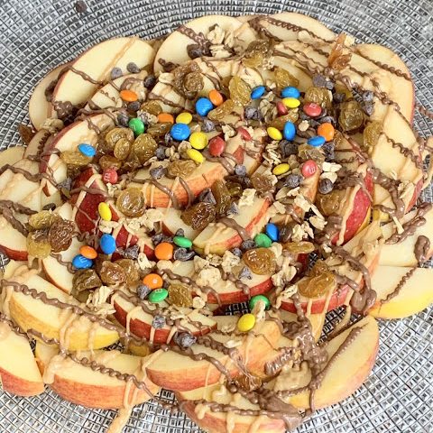 pile of apples covered in chocolate, peanut butter, m+ms, dried fruit, and chocolate chips.